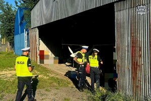 Na zdjęciu policjanci przy hangarze.