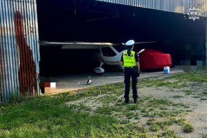 Na zdjęciu policjantka przy hangarze.