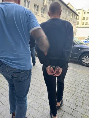 policjant idzie z zatrzymanym.