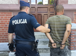 policjant idzie z zatrzymanym.