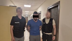 Dwaj policjanci prowadzą zatrzymanego mężczyznę.