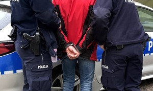 Dwaj policjanci prowadzą zatrzymanego.