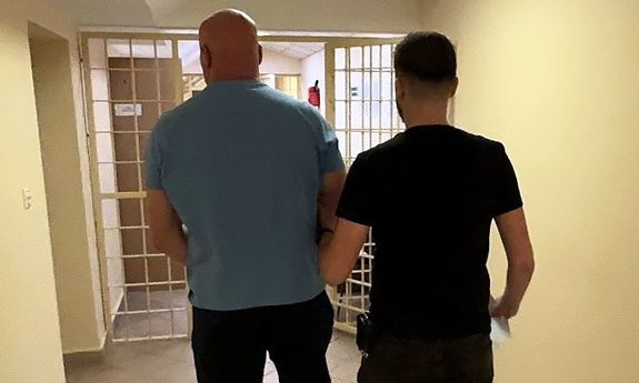 policjant prowadzi zatrzymanego.