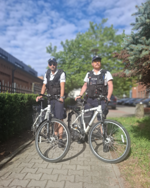 dwóch policjantów stoi obok swoich rowerów.