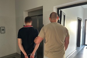 Funkcjonariusz prowadzi zatrzymanego.