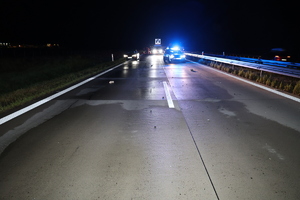 Pora nocna. Miejsce zdarzenia na autostradzie A4 - z przodu widać policyjny radiowóz, z boku uszkodzony samochód.