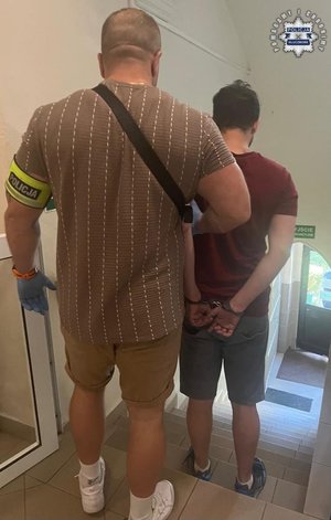 Policjant prowadzi zatrzymanego.
