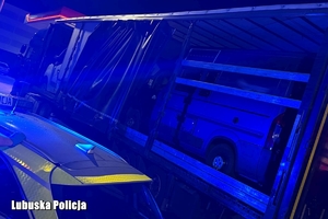Radiowóz obok naczepy z busami.