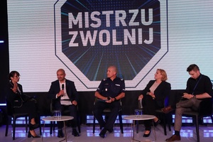 Uczestnicy inauguracji kampanii siedzą na krzesłach ustawionych na scenie. W tle na ekranie wyświetlany slajd z logiem Mistrzu zwolnij.