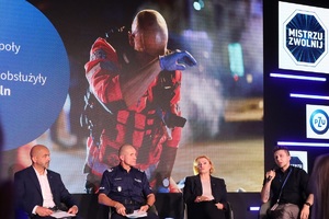 Uczestnicy inauguracji kampanii siedzą na krzesłach ustawionych na scenie. W tle na ekranie wyświetlany slajd.
