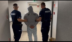 policjanci prowadzą zatrzymanego.