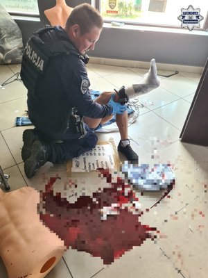 Zdjęcie przedstawia policjanta udzielającego pierwszej pomocy.
