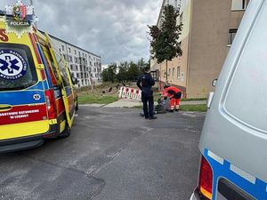 karetka i radiowóz. obok poszkodowanego stoją ratownicy medyczni i policjant.