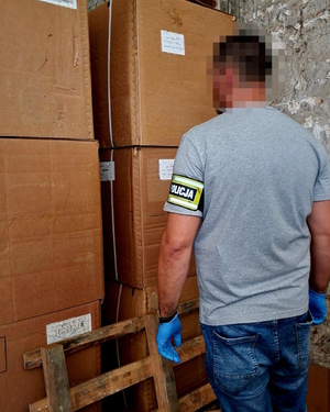 Policjant stoi przy kartonach.