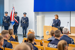 Z lewej widoczny poczet sztandarowy policjantów z prawej przy mównicy insp. dr Monika Porwisz, Zastępca Komendanta-Prorektor.