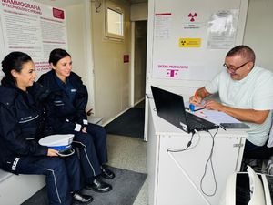 Policjantki siedzą na przeciwko stolika, za którym siedzi ubrany na biało mężczyzna.