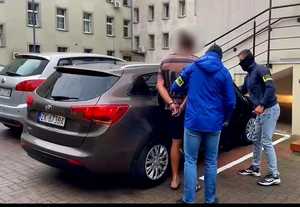 Policjanci z zatrzymanym przy samochodzie.