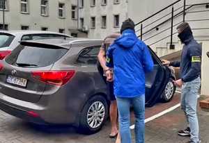 Policjanci z zatrzymanym przy samochodzie.