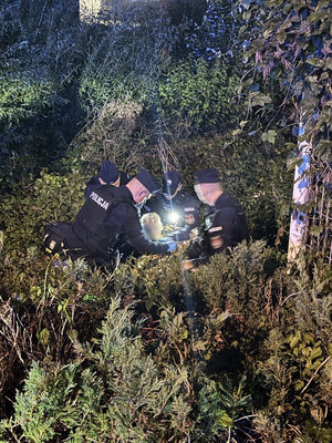Policjanci z odnaleziona kobietą w zaroślach.