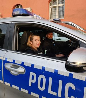 Policjant i policjantka siedzą w radiowozie.