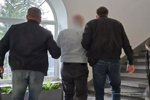 Dwaj policjanci prowadzą zatrzymanego.