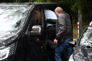 Dwaj policjanci prowadzą zatrzymanego.