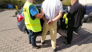 Policjanci prowadzą zatrzymanego.
