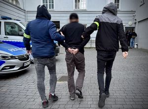 policjanci prowadzą zatrzymanego.