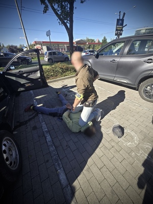 Policjant z leżącym na ziemi zatrzymanym.