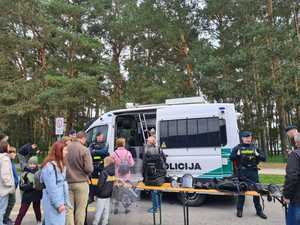 Litewscy policjanci przy radiowozie - z przodu ludzie, którzy przyszli obejrzeć wystawiony na ławkach policyjny sprzęt.