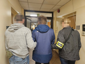 Dwaj policjanci prowadzą zatrzymanego.
