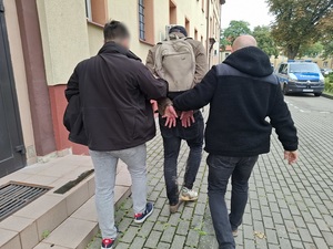 Dwaj policjanci prowadzą zatrzymanego.