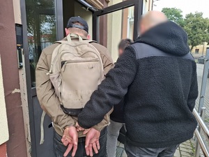 Dwaj policjanci prowadzą zatrzymanego.