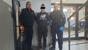 Dwaj policjanci z zatrzymanym mężczyzną w kajdankach.