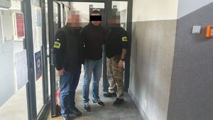 Dwaj policjanci z zatrzymanym mężczyzną w kajdankach.