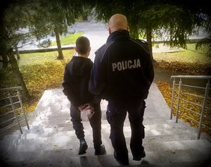 policjant idzie z zatrzymanym.