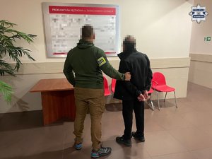 Policjant z zatrzymanym mężczyzną na korytarzu w budynku Prokuratury Rejonowej w Tarnowskich Górach.