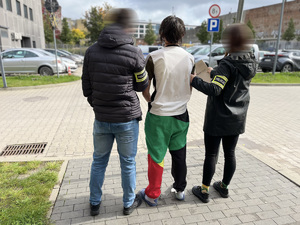 policjanci stoją z zatrzymanym.