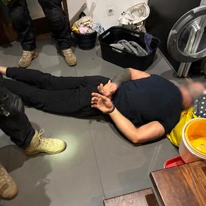 Zatrzymany zakuty w kajdanki leży na podłodze.