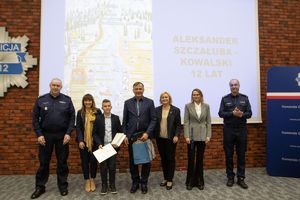 dzieci z policjantami pozują na tle swoich prac.