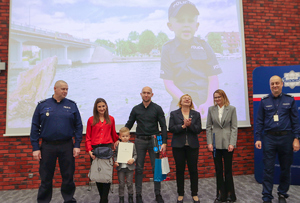 dzieci z policjantami pozują na tle swoich prac.