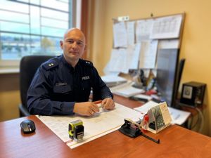 Umundurowany policjant siedzi za biurkiem.