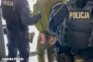 Policjanci prowadzą zatrzymanego mężczyznę.