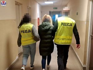 Dwoje policjantów prowadzi zatrzymaną kobietę.