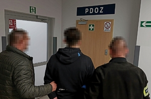 Dwaj policjanci prowadzą zatrzymanego.