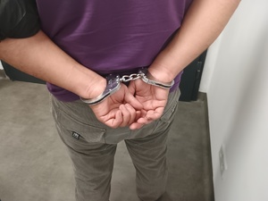 Zatrzymany mężczyzna w kajdankach na rękach.