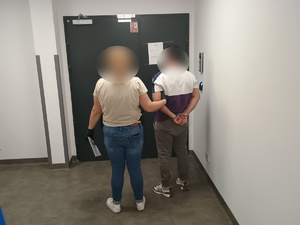 Zatrzymany prowadzony przez policjantkę w ubraniu cywilnym.