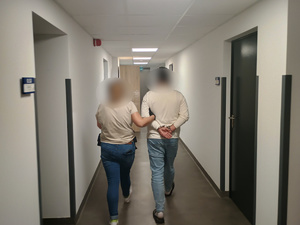 Zatrzymany prowadzony przez policjantkę w ubraniu cywilnym.