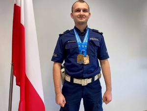 Umundurowany policjanta z dwoma medalami na szyi.