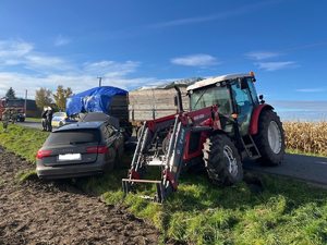 Pojazdy, które uczestniczyły w wypadku. Traktor z podczepionymi dwoma przyczepami przykrytymi plandekami o raz samochód, który uderzył w jedną z przyczep.